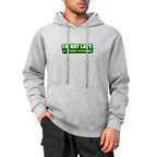 Modelo com sweatshirt cinzenta de capuz, bolso canguru e inscrição verde I’m Not Lazy, I’m Energy Efficient.