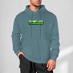 Sweatshirt cinzento-ardósia com capuz e inscrição verde I’m Not Lazy, I’m Energy Efficient, usada por um modelo.